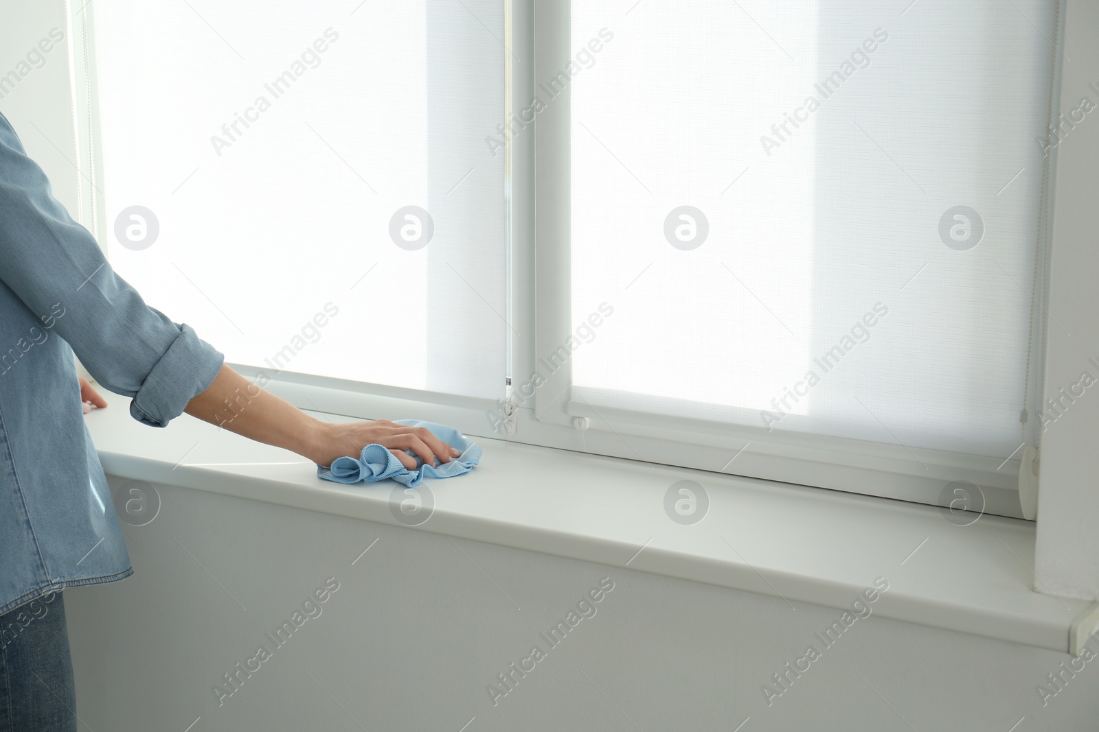 Photo of Woman cleaning window sill with rag, closeup