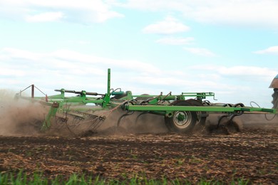 Photo of Planter cultivating field on spring day. Agricultural industry