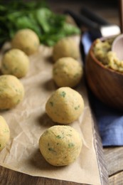 Photo of Wooden board with raw falafel balls on table, closeup