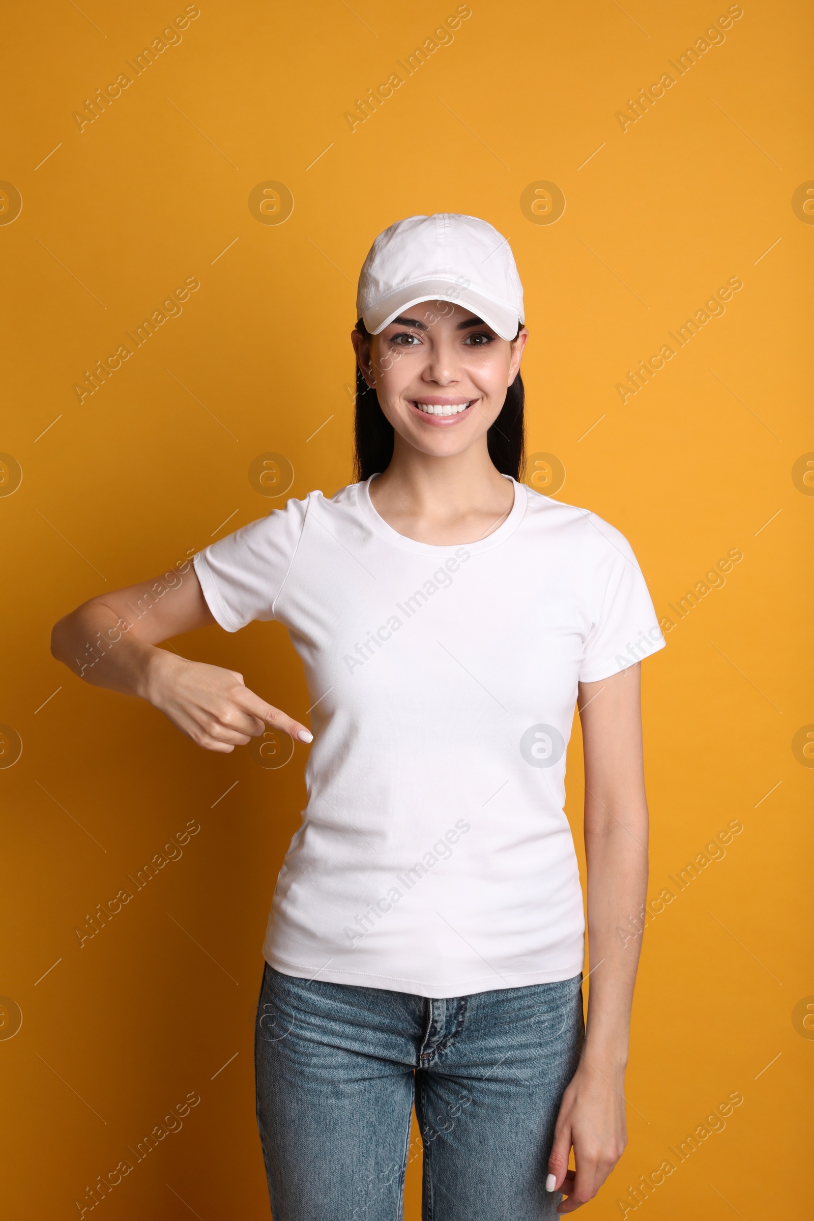 Photo of Young happy woman in white cap and tshirt on yellow background. Mockup for design