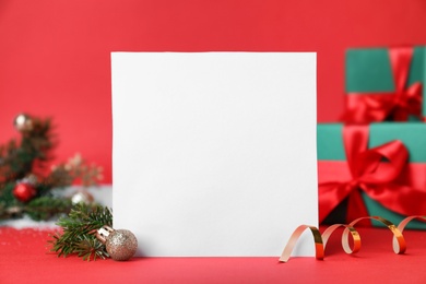 Blank Christmas card and festive decor on red background. Space for text