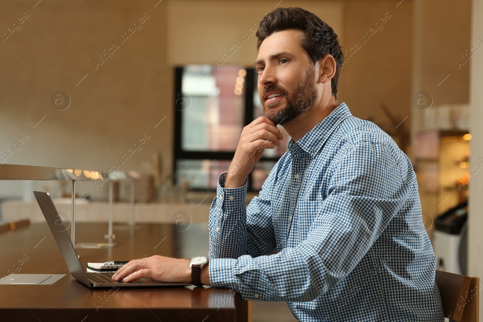 Photo of Man with laptop at table in cafe