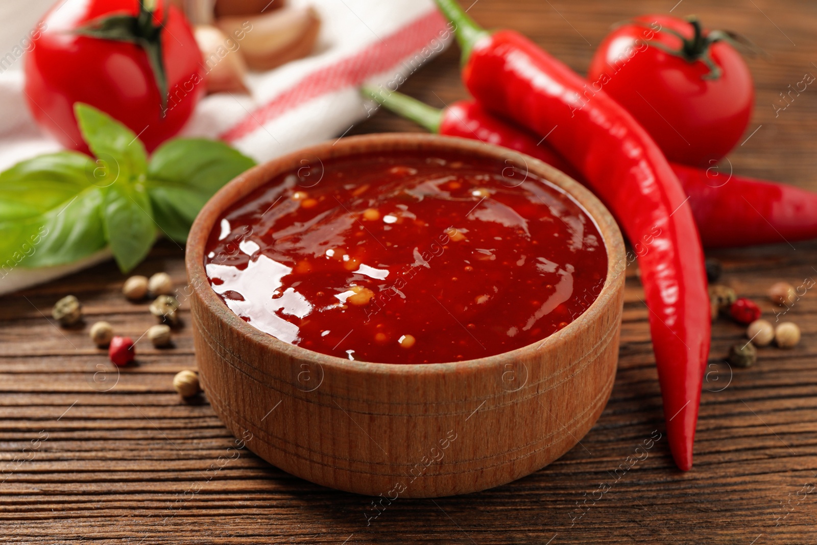 Photo of Spicy chili sauce in bowl on wooden table