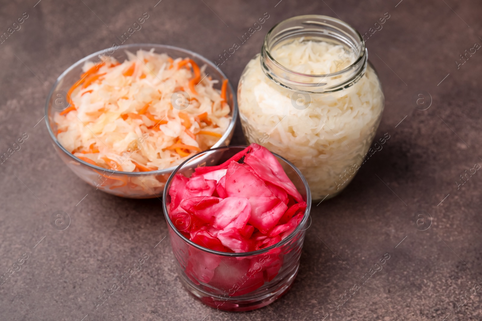 Photo of Delicious sauerkraut prepared according to different recipes on brown table