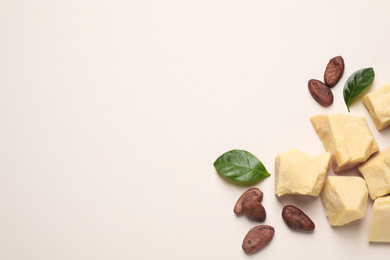Organic cocoa butter and beans on beige background, flat lay. Space for text