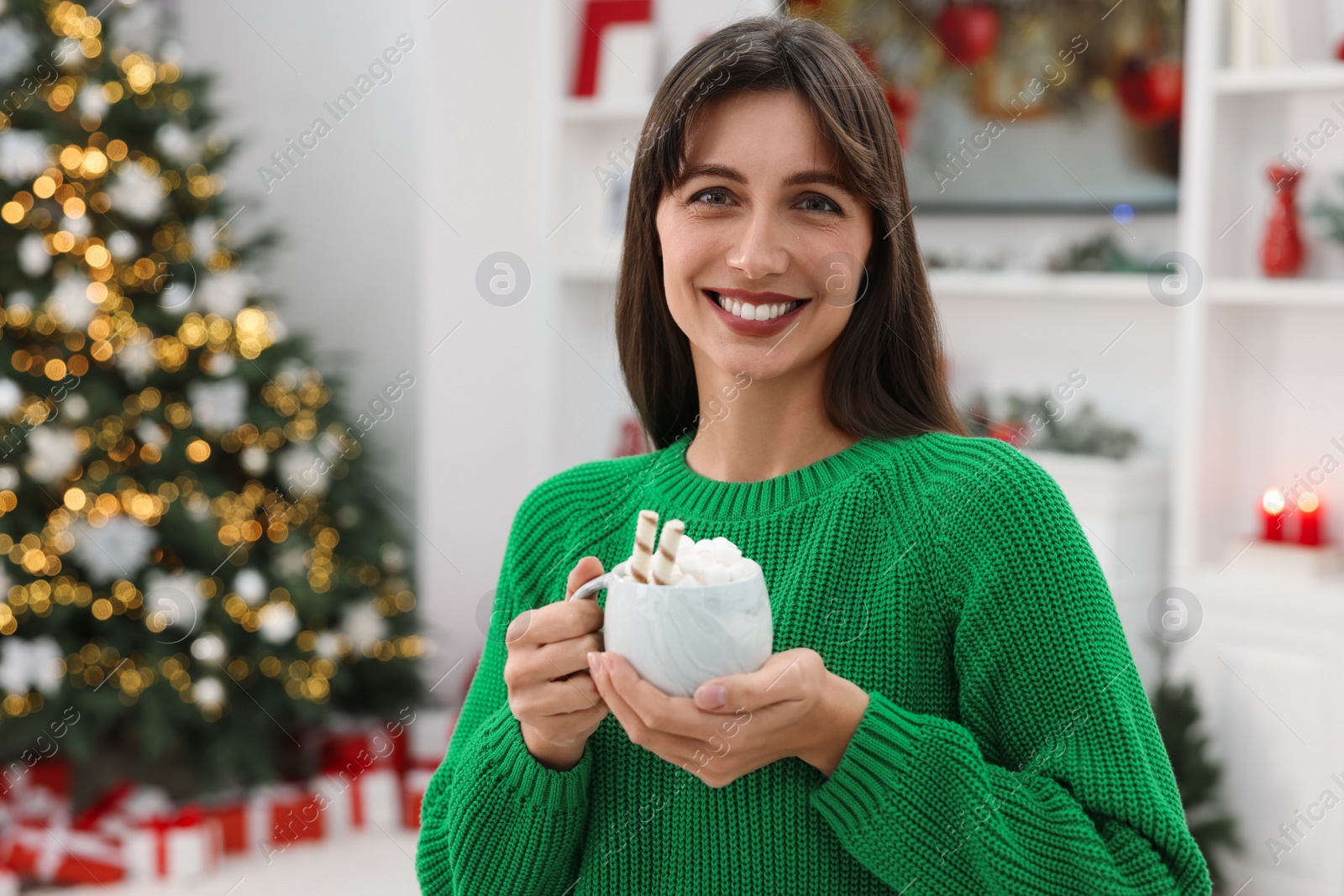 Photo of Smiling woman holding cup of Christmas cocoa with marshmallows at home. Space for text