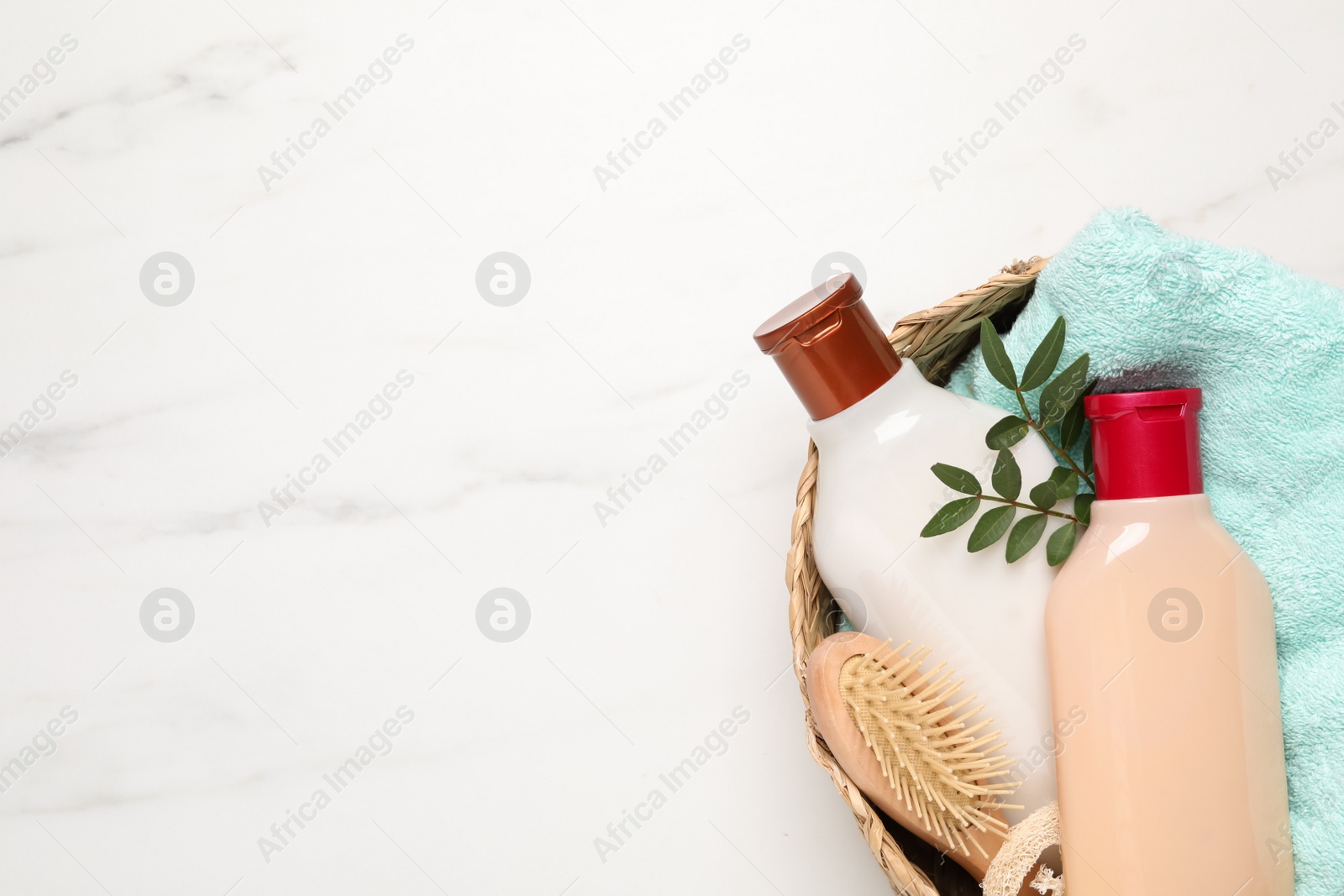 Photo of Shampoo bottles, hair brush, towel and leaves on white marble table, top view. Space for text