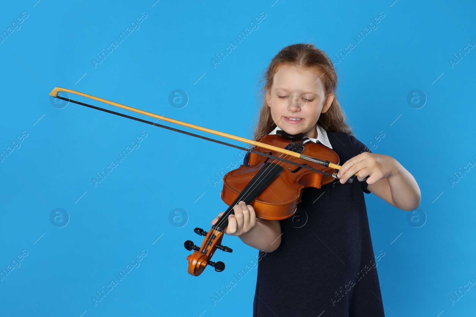 Photo of Preteen girl playing violin on light blue background