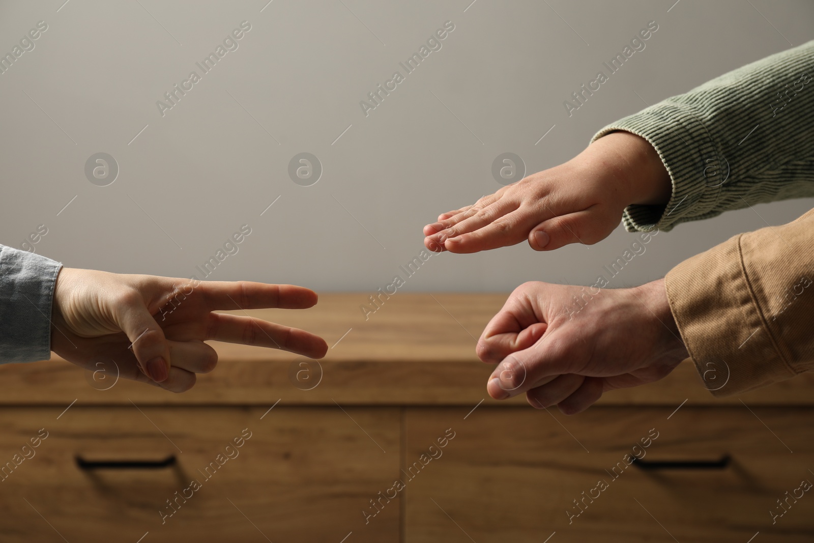 Photo of People playing rock, paper and scissors indoors, closeup