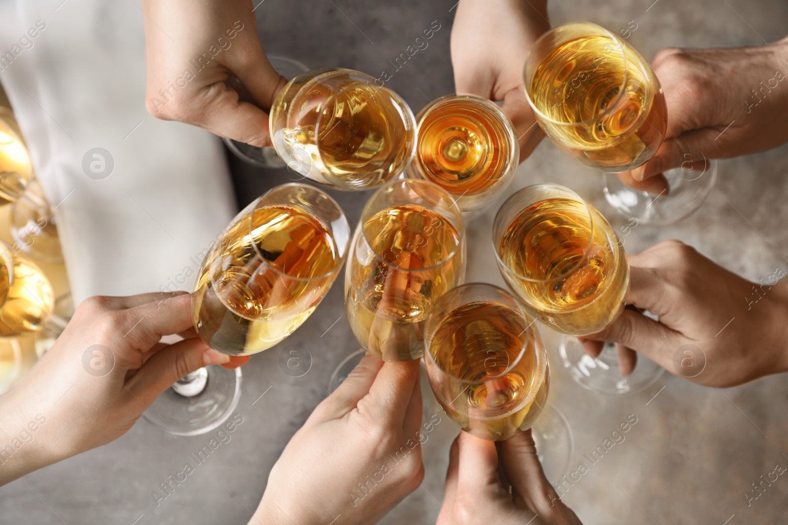 Photo of People clinking glasses with champagne over table, top view