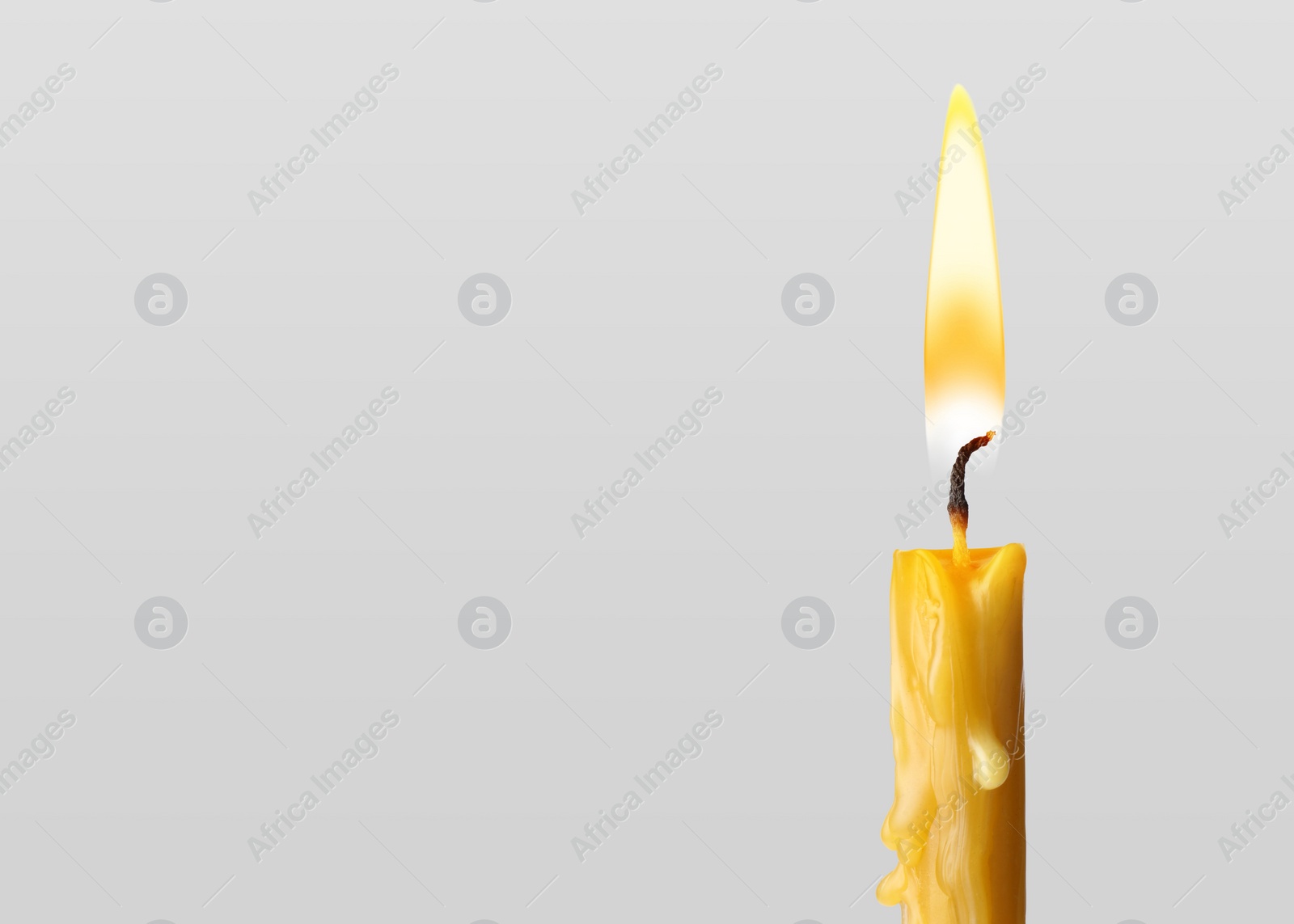 Image of Burning church candle on light background. Space for text