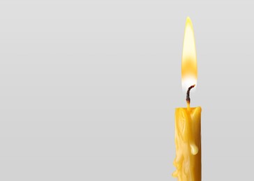 Image of Burning church candle on light background. Space for text