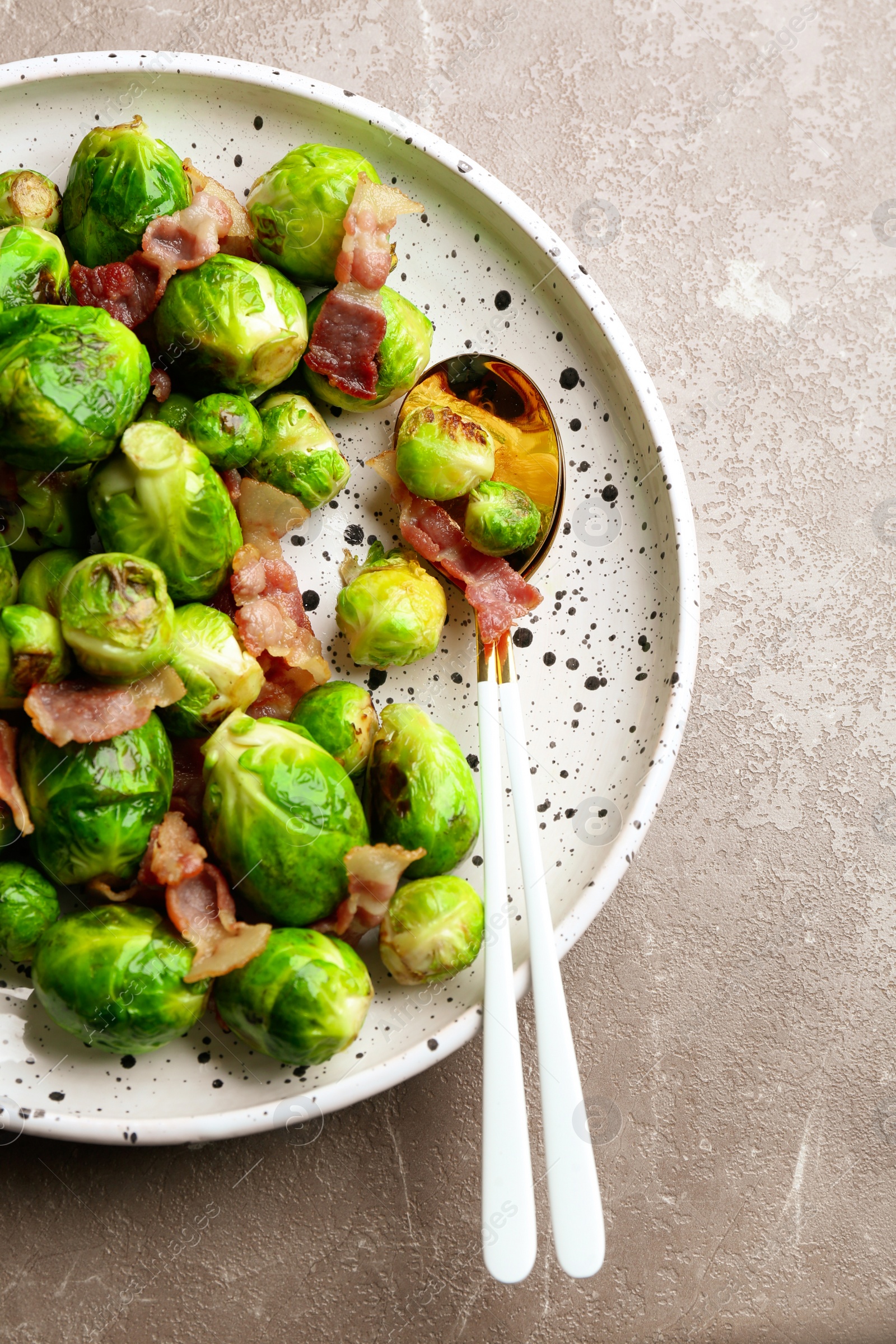 Photo of Delicious Brussels sprouts with bacon on marble table, top view