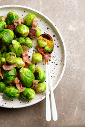 Delicious Brussels sprouts with bacon on marble table, top view