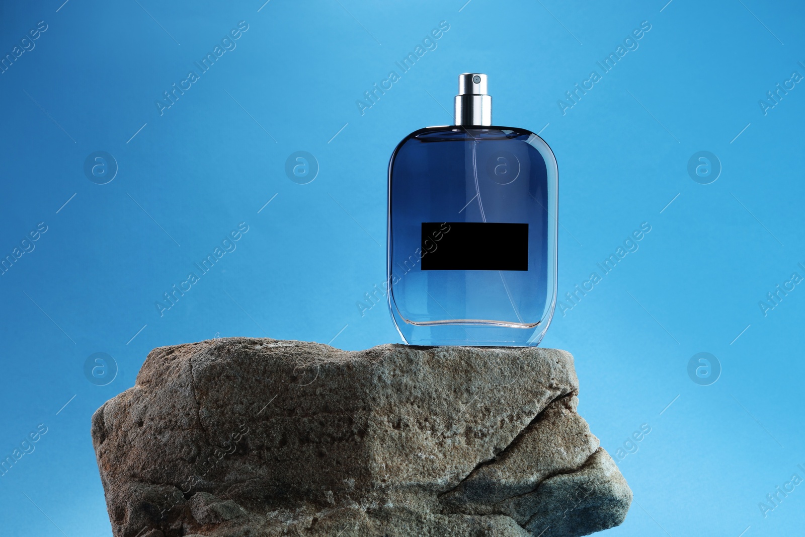 Photo of Stylish presentation of luxury men`s perfume on stone against light blue background