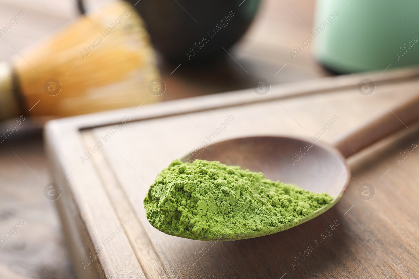 Photo of Spoon with powdered matcha tea on wooden board, closeup