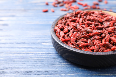 Photo of Dried goji berries on blue wooden table, closeup