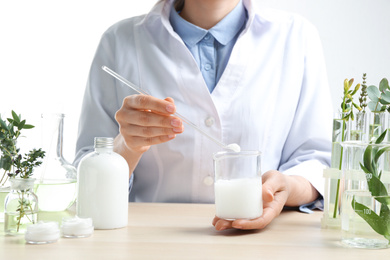 Woman with natural cream in cosmetic laboratory, closeup