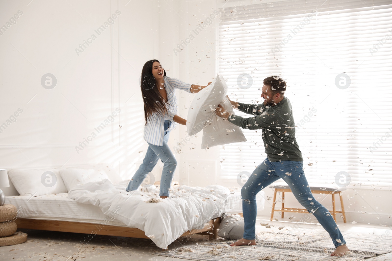 Photo of Happy young couple having fun pillow fight in bedroom