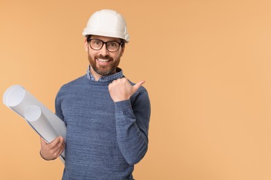 Architect in hard hat with drafts pointing at something on beige background, space for text