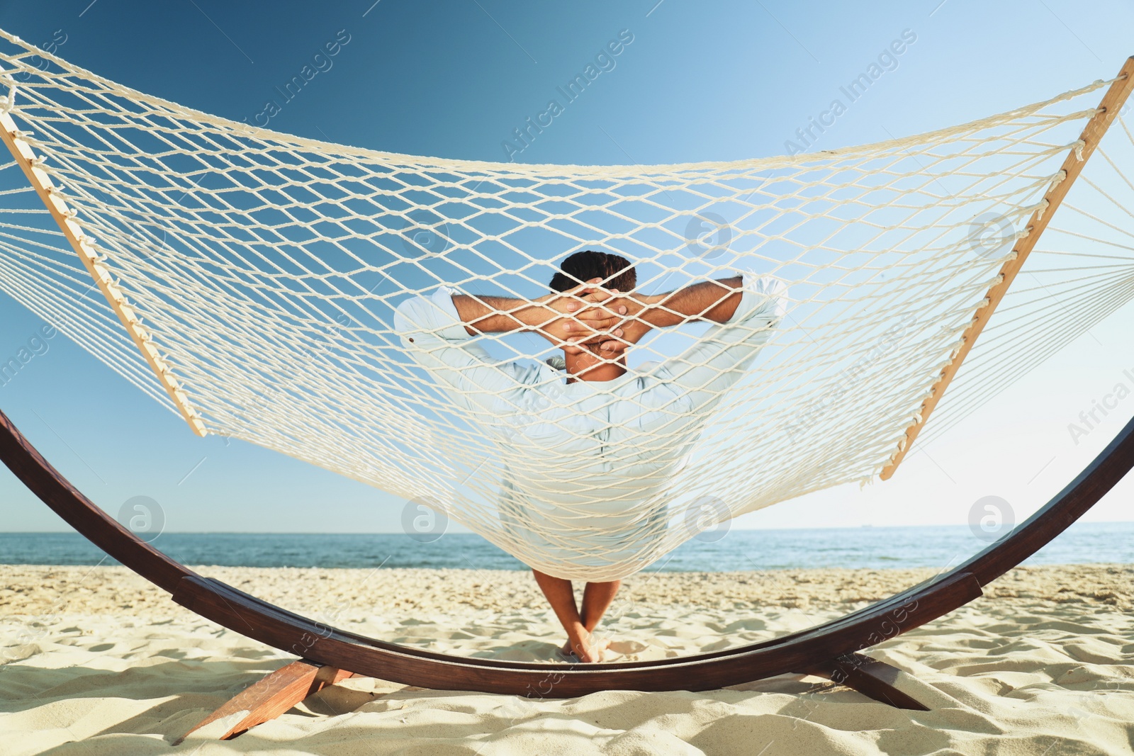 Photo of Man relaxing in hammock on beach. Summer vacation