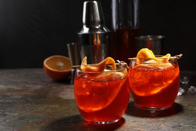 Photo of Aperol spritz cocktail, ice cubes and orange slices in glasses on grey textured table