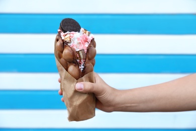 Young woman holding delicious sweet bubble waffle with ice cream on color background, closeup