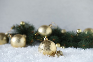 Photo of Beautiful Christmas balls and fir branches on snow. Space for text