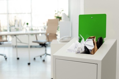 Open full trash bin in modern office, space for text. Waste recycling