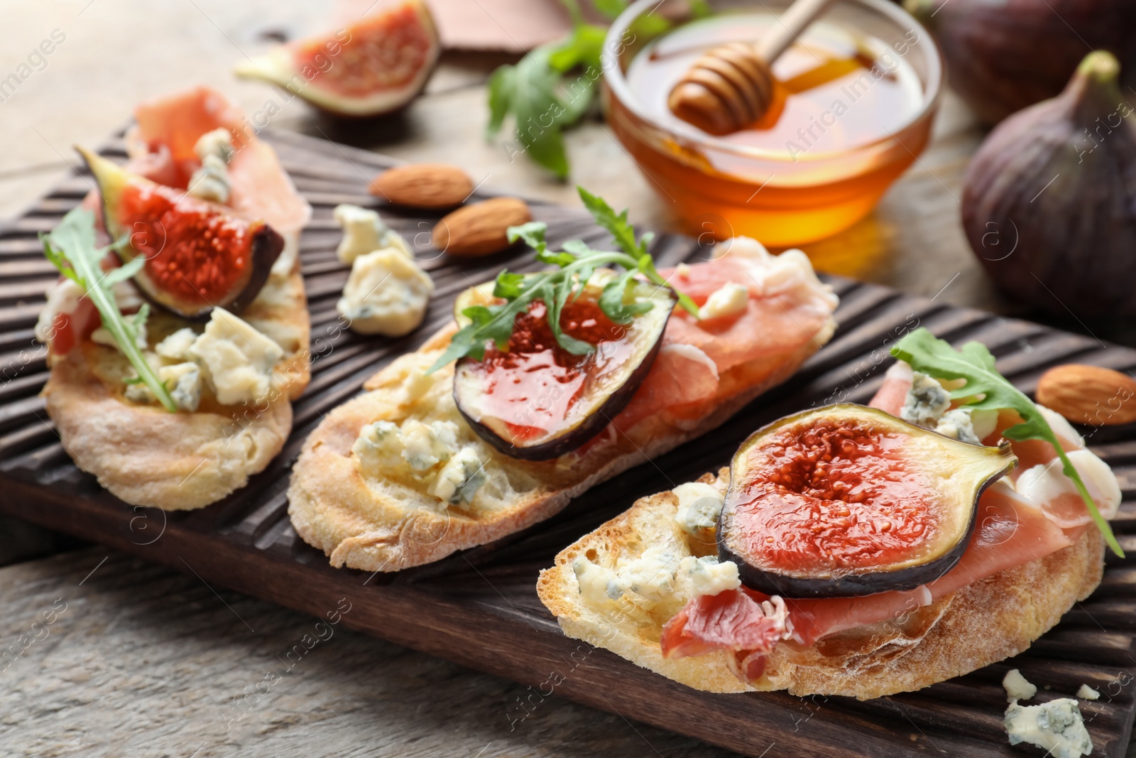 Photo of Sandwiches with ripe figs and prosciutto served on wooden table, closeup