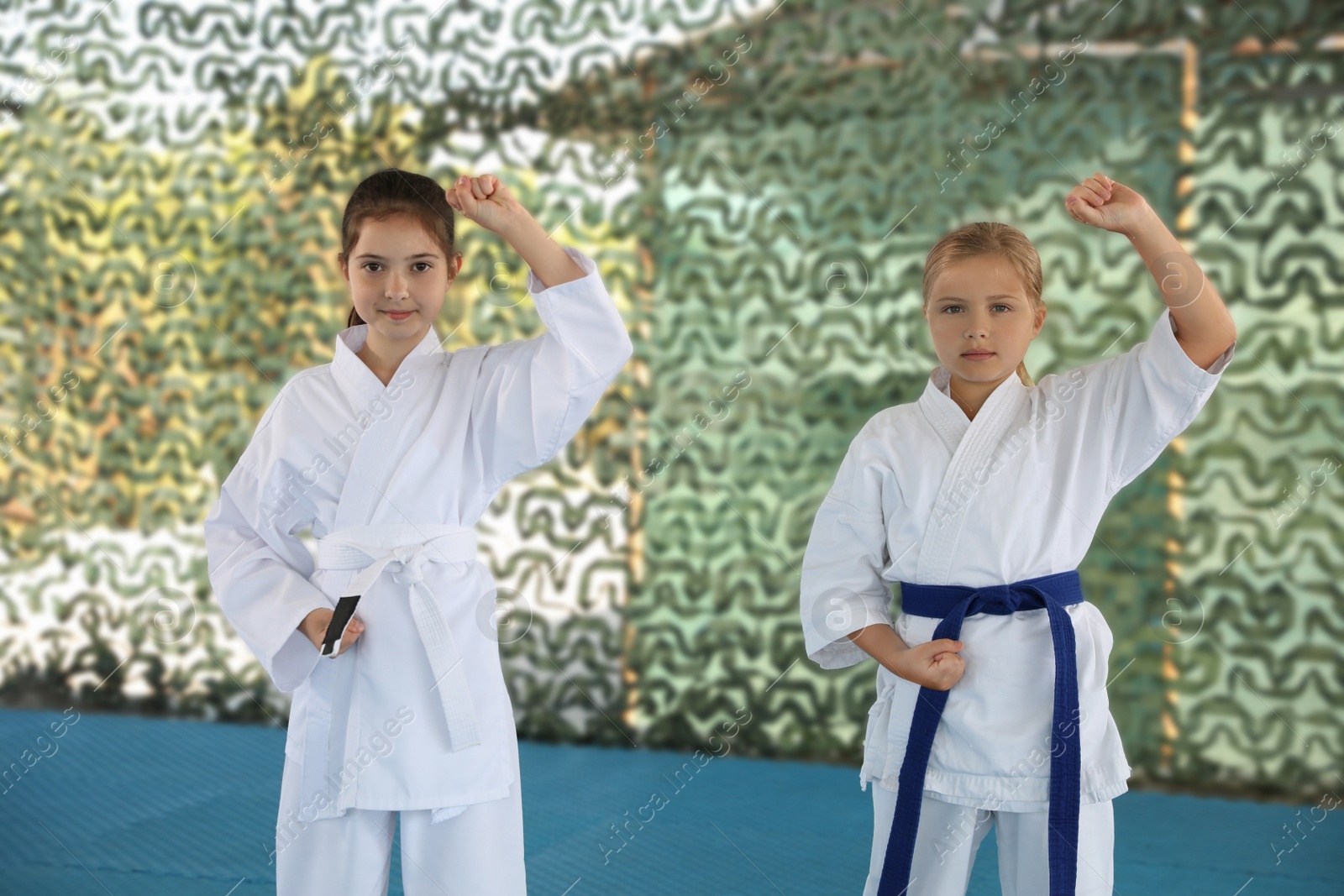 Photo of Children in kimono practicing karate on tatami outdoors