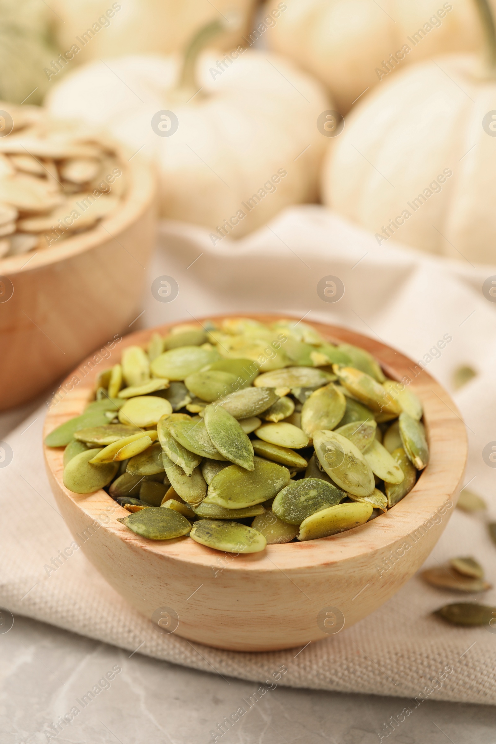 Photo of Wooden bowl with pumpkin seeds on table