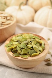 Photo of Wooden bowl with pumpkin seeds on table