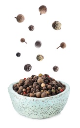 Image of Many different peppercorns falling into bowl on white background