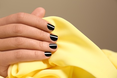 Photo of Woman with black manicure holding color fabric, closeup. Nail polish trends
