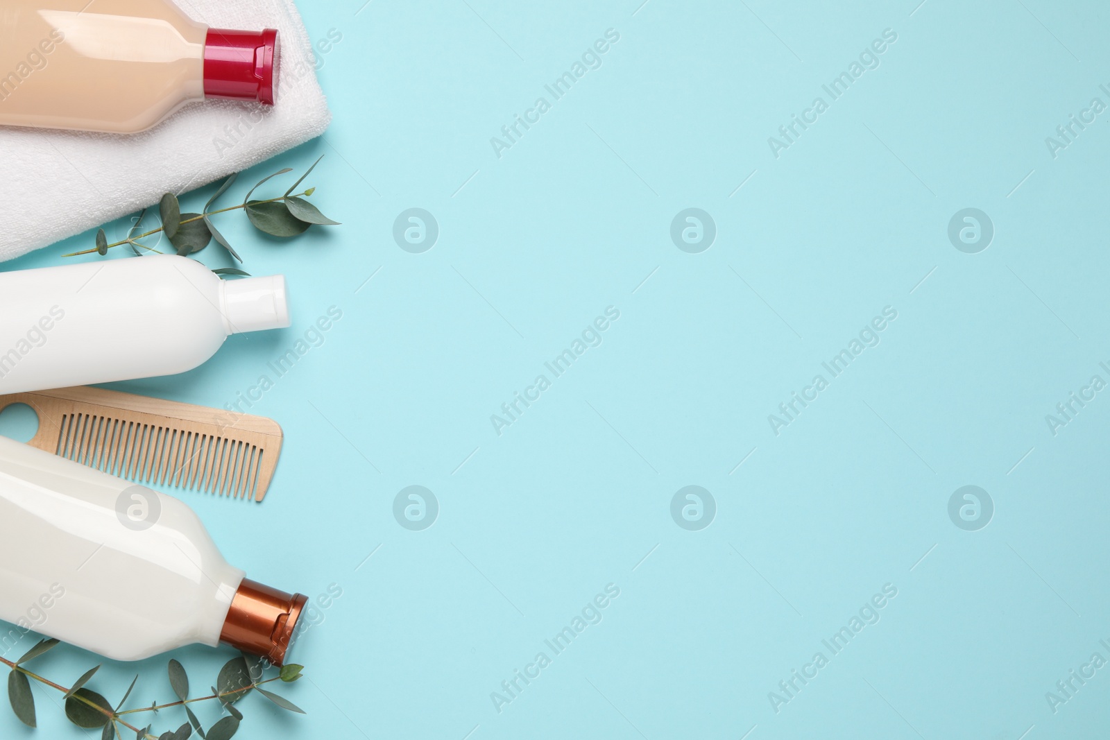 Photo of Shampoo bottles, wooden comb, towel and leaves on turquoise background, flat lay. Space for text