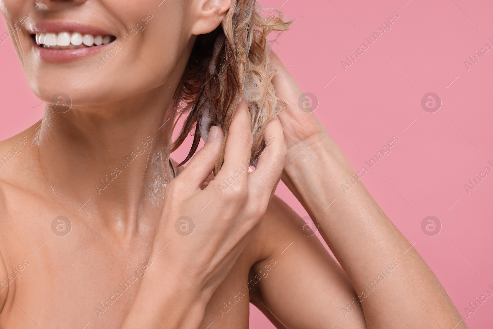 Photo of Happy woman washing hair on pink background, closeup