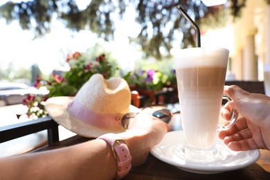 Photo of Young woman with coffee at table in outdoor cafe, closeup