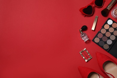 Flat lay composition with stylish women's shoes and different makeup products on red background. Space for text