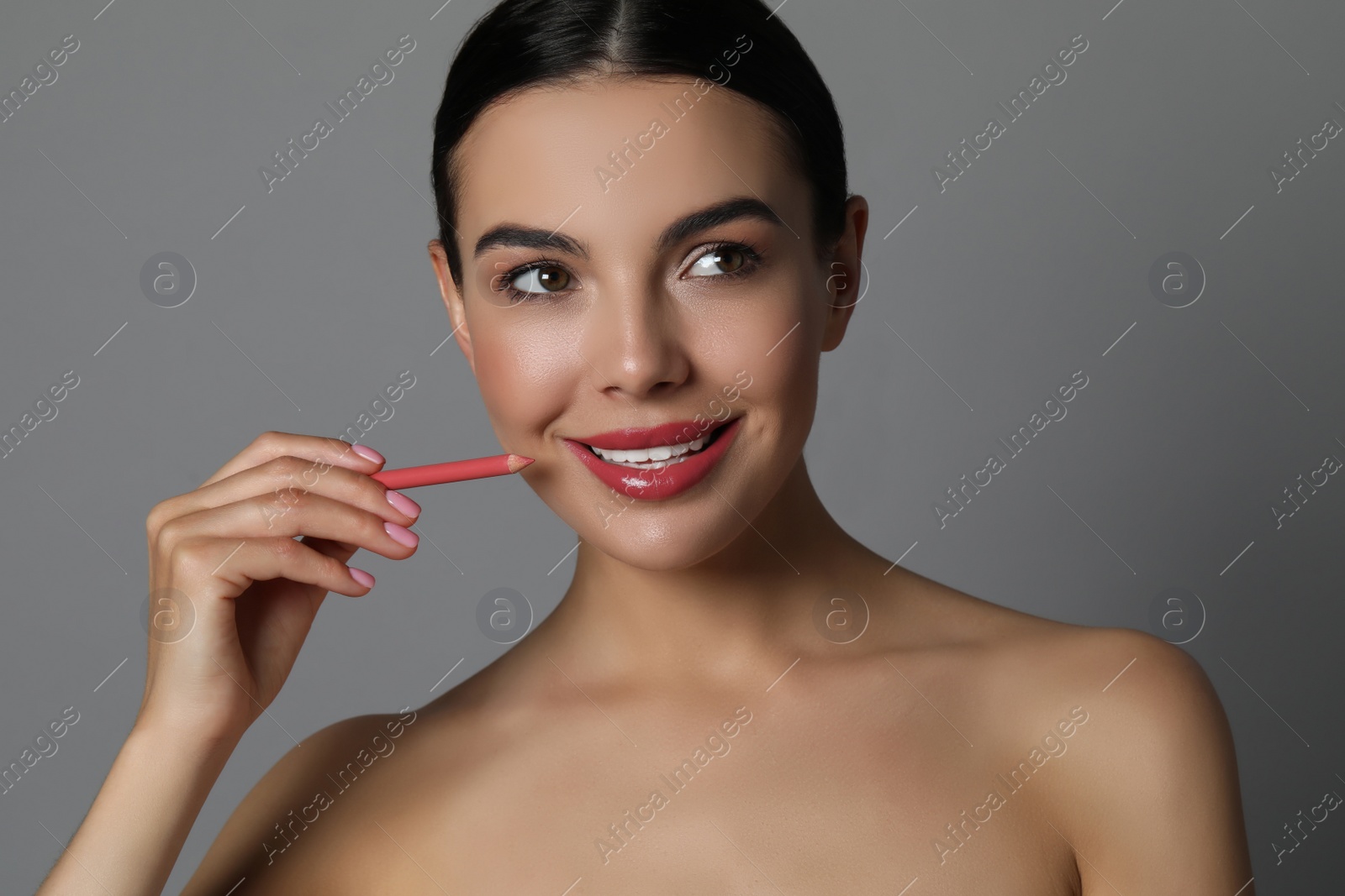 Photo of Pretty young woman with beautiful pink lip pencil on grey background