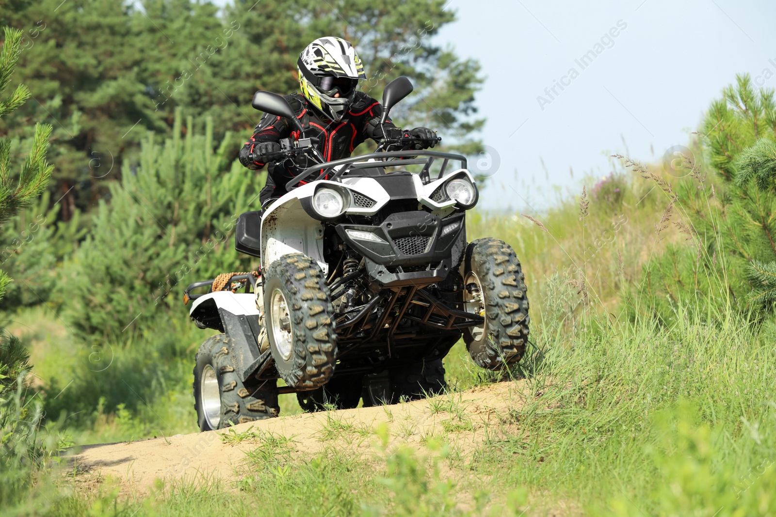 Photo of Man driving modern quad bike on sandy road near forest. Extreme sport