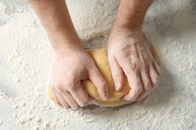 Photo of Young man kneading dough for pasta on table