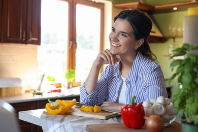 Young woman at countertop with fresh cut bell peppers in kitchen, space for text