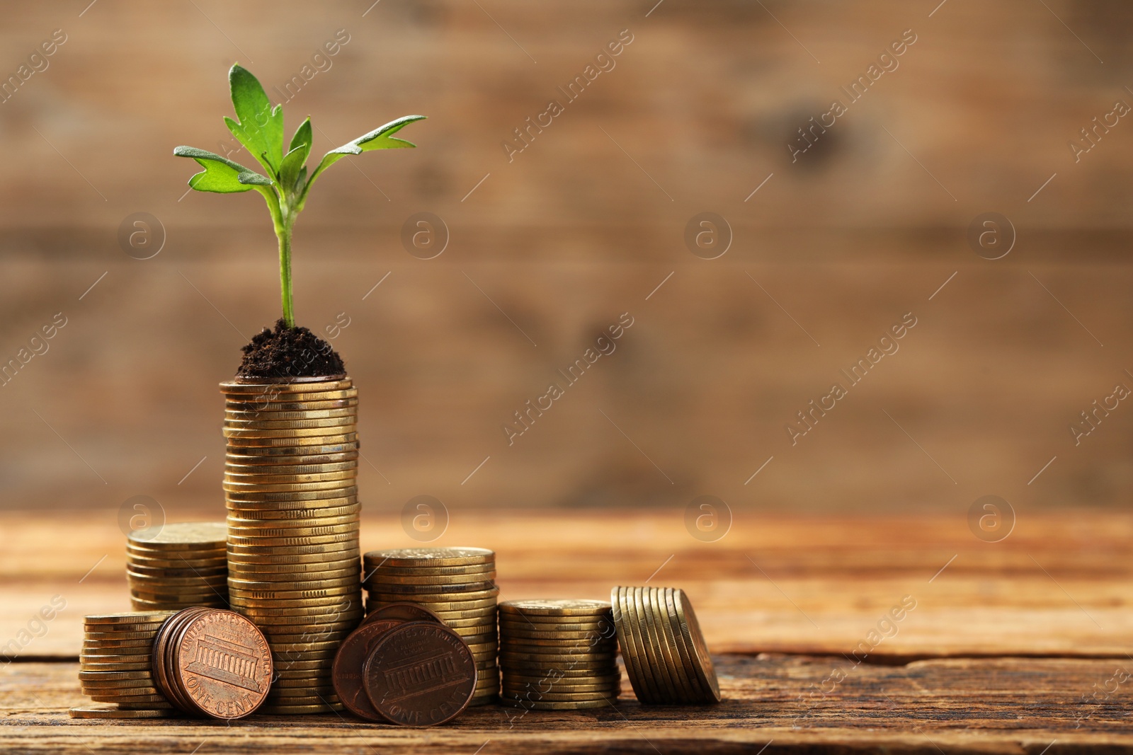 Photo of Stacks of coins with green sprout on wooden table, space for text. Investment concept
