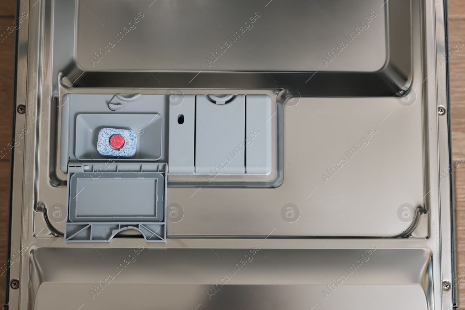 Photo of Open dishwasher door with detergent tablet, top view