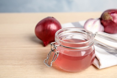 Photo of Glass jar with onion syrup and fresh ingredient on wooden table. Space for text