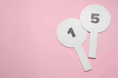 Auction paddles with numbers on pink background, top view. Space for text