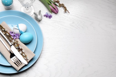 Photo of Festive Easter table setting with eggs on white wooden background, flat lay. Space for text