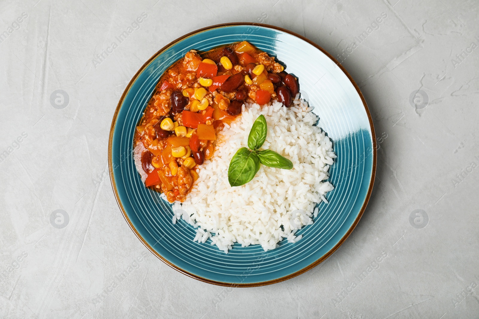 Photo of Plate of rice with chili con carne on gray background, top view