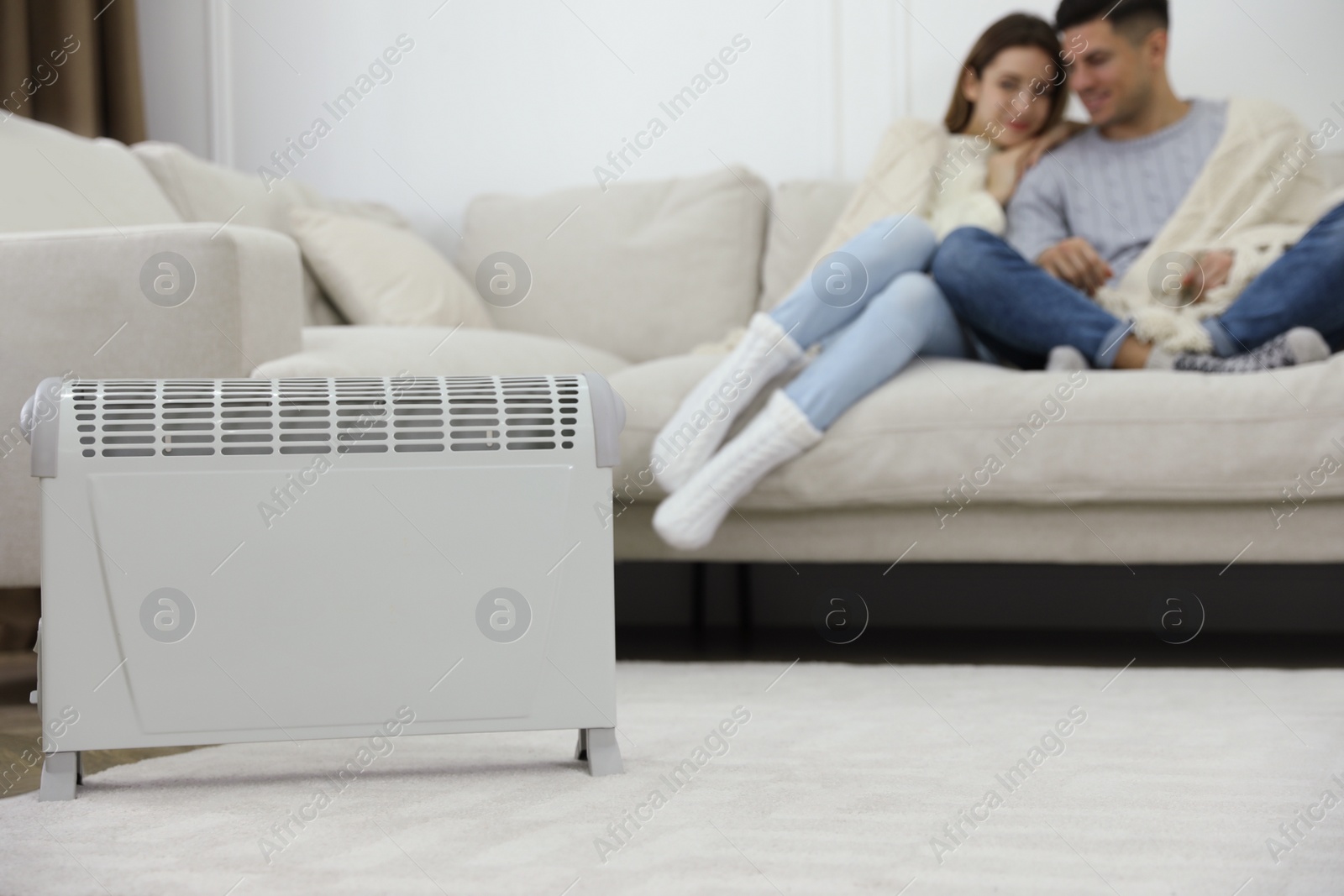 Photo of Electric heater and couple on sofa at home
